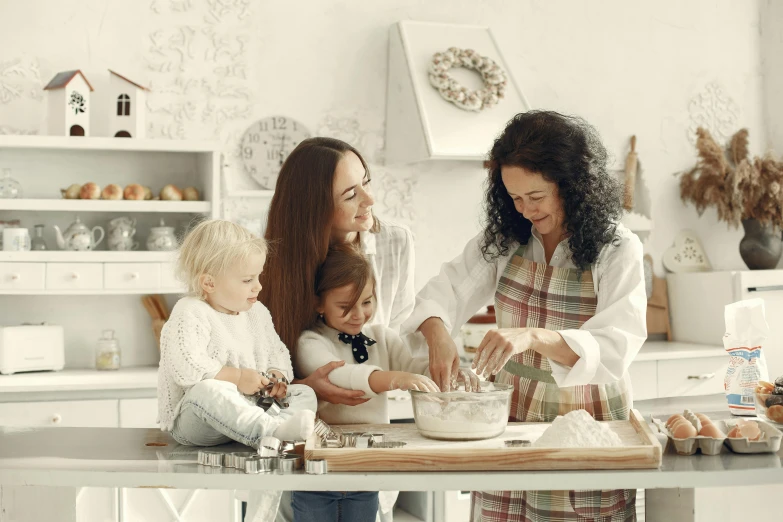 a group of women and children are sitting around a table in the kitchen