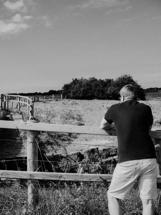 a man on a farm looking over a wooden fence