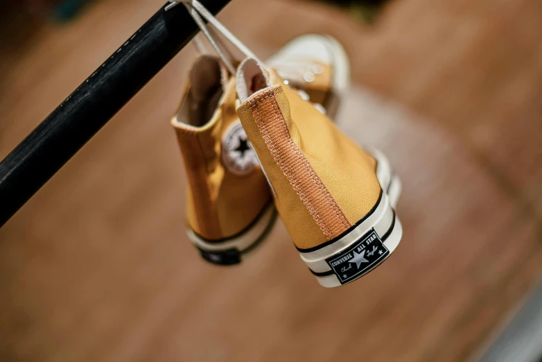 a pair of yellow shoes hanging from a black pole