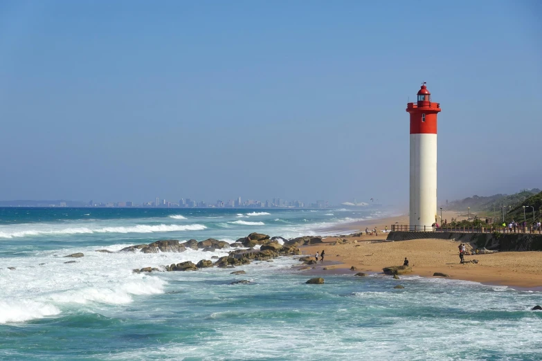 a large white and red lighthouse next to the ocean