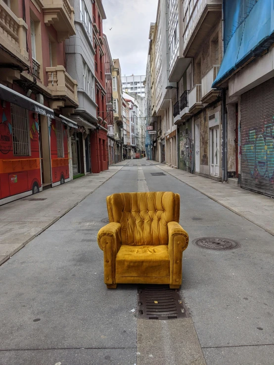 an odd looking couch sits on a street between two large buildings