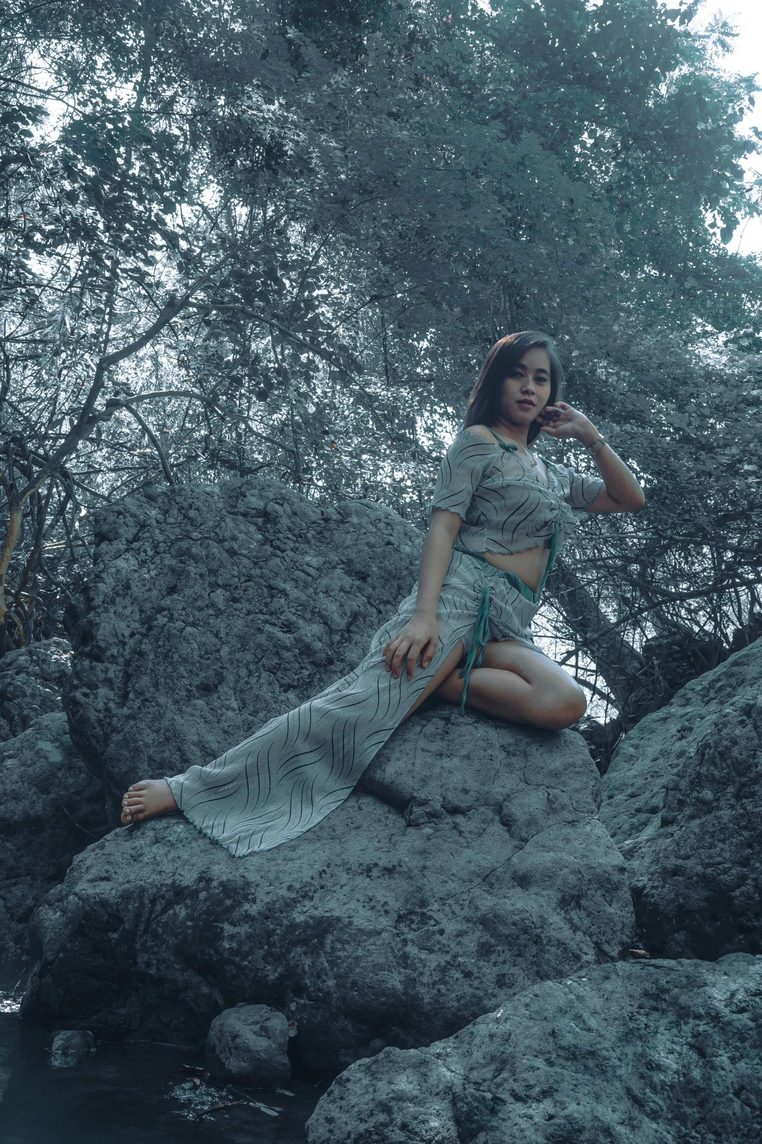 a woman sitting on a rock with trees in the background