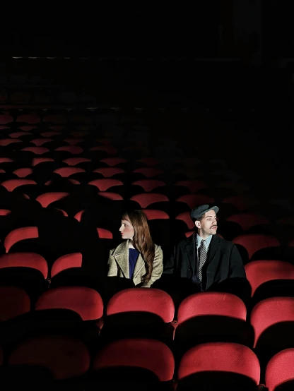 a couple of people sit on the floor in a theatre