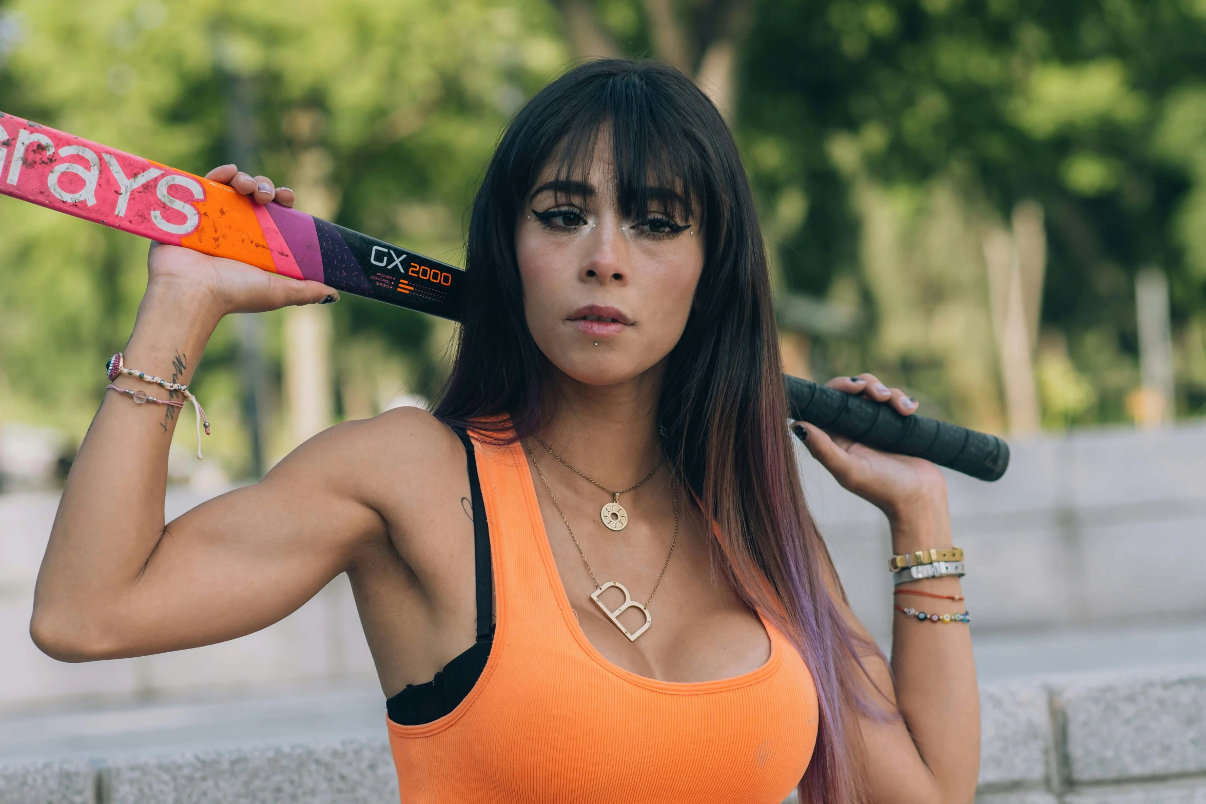 young woman holding baseball bat on her shoulder looking over shoulder