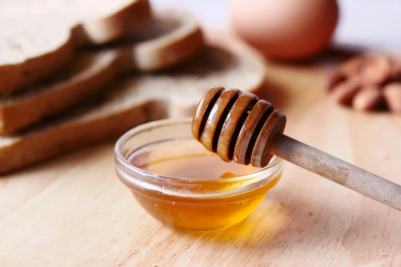 a glass jar filled with honey next to slices of bread