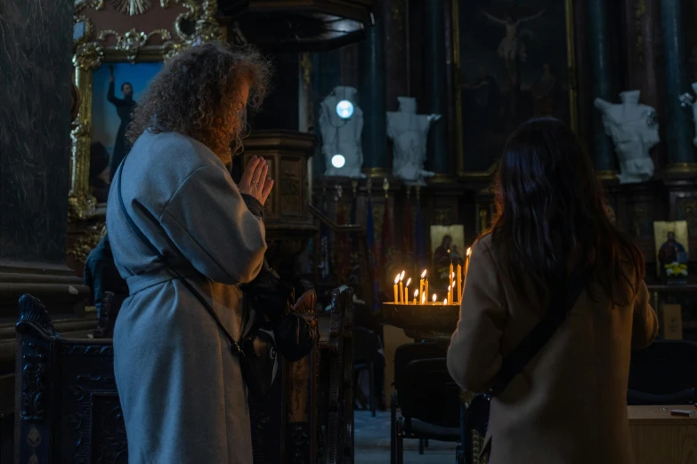 two people standing by a fireplace with some candles on them