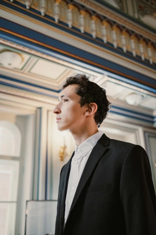 a person in a suit standing in front of a window