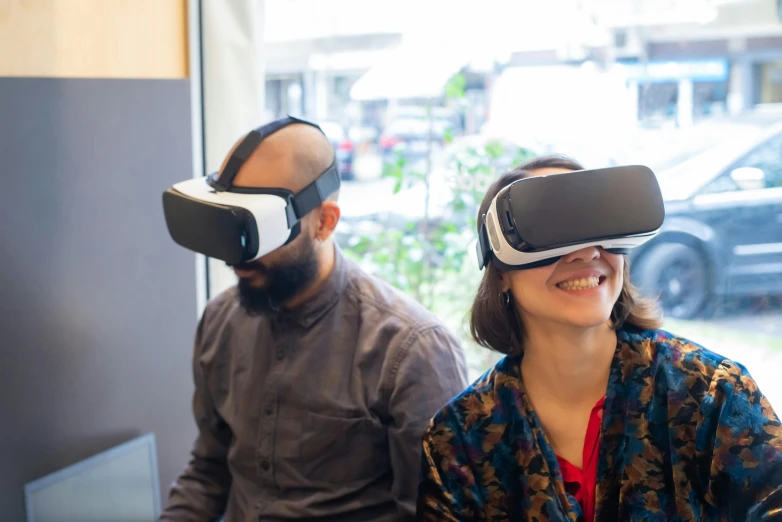 a man wearing virtual reality glasses with the help of a woman