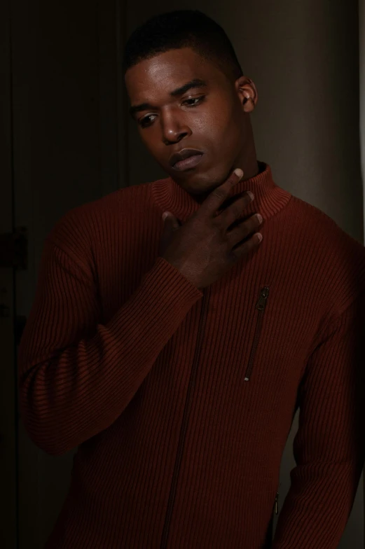 a man in a red sweater has his hand under his collar