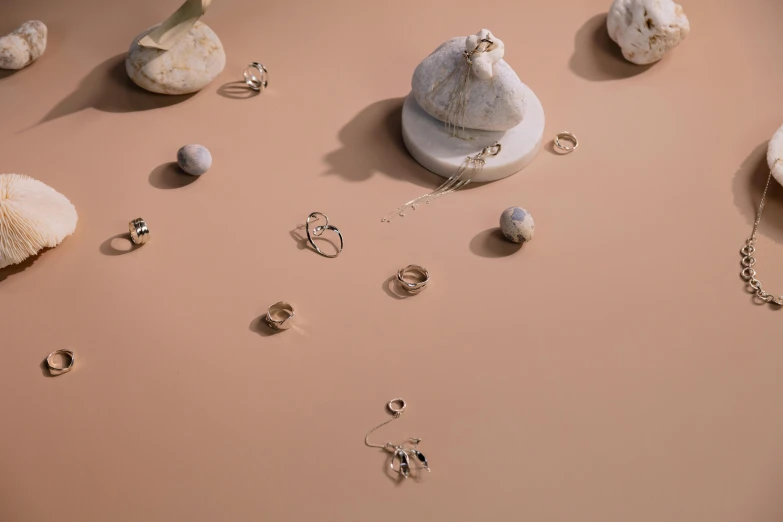 a small bag and several pairs of earrings on a pink surface