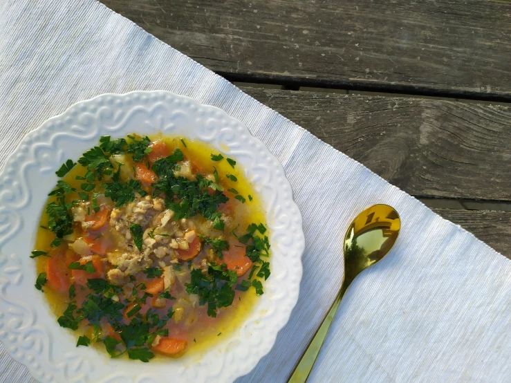 a plate of soup with silverware on an old wood table