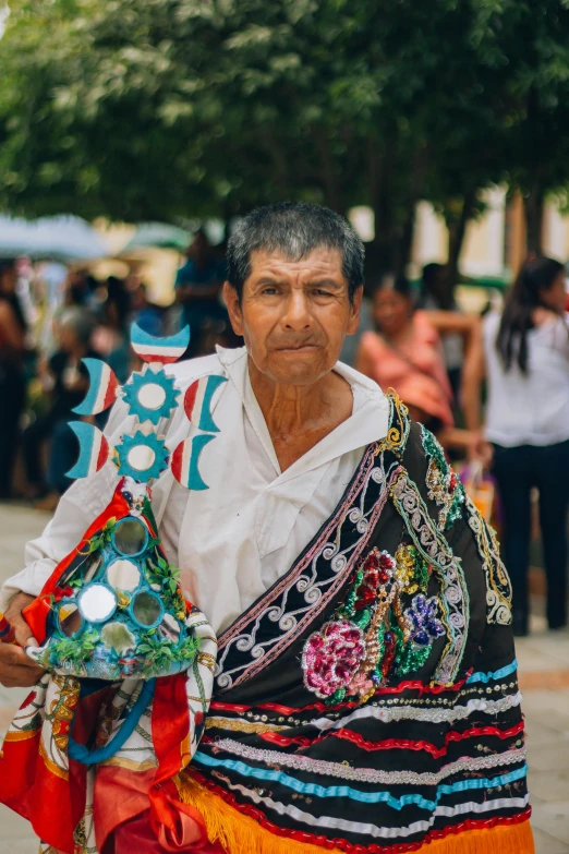 a man wearing a skirt with colorful ribbons is carrying soing