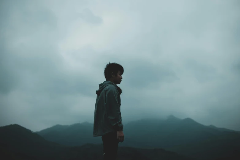 a man standing on a mountain under a cloudy sky