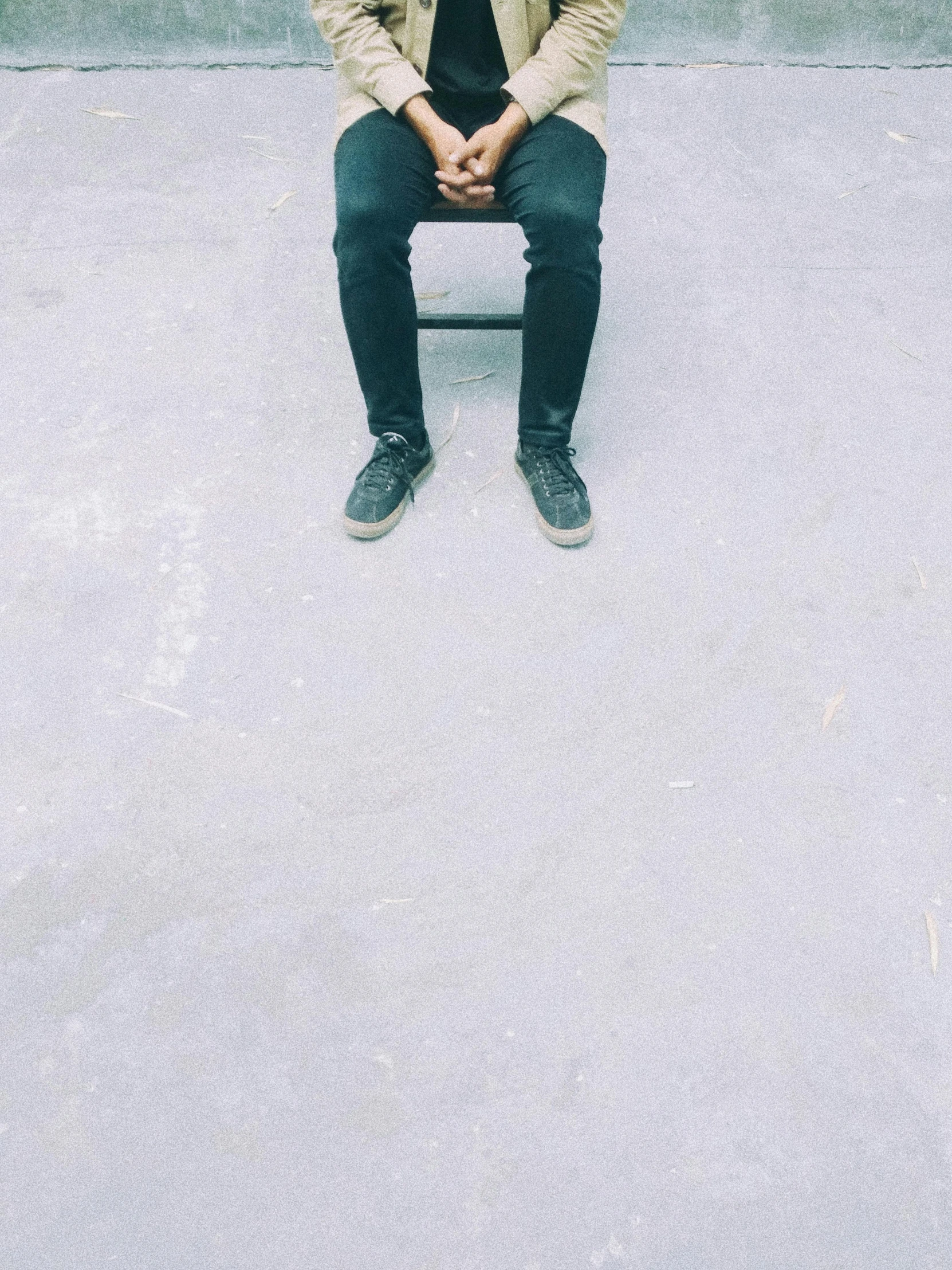 man sitting on a bench outside near a wall