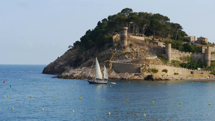 a boat in the water near a small island with a castle on top