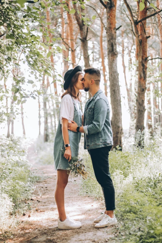 two people are kissing on the ground near some trees
