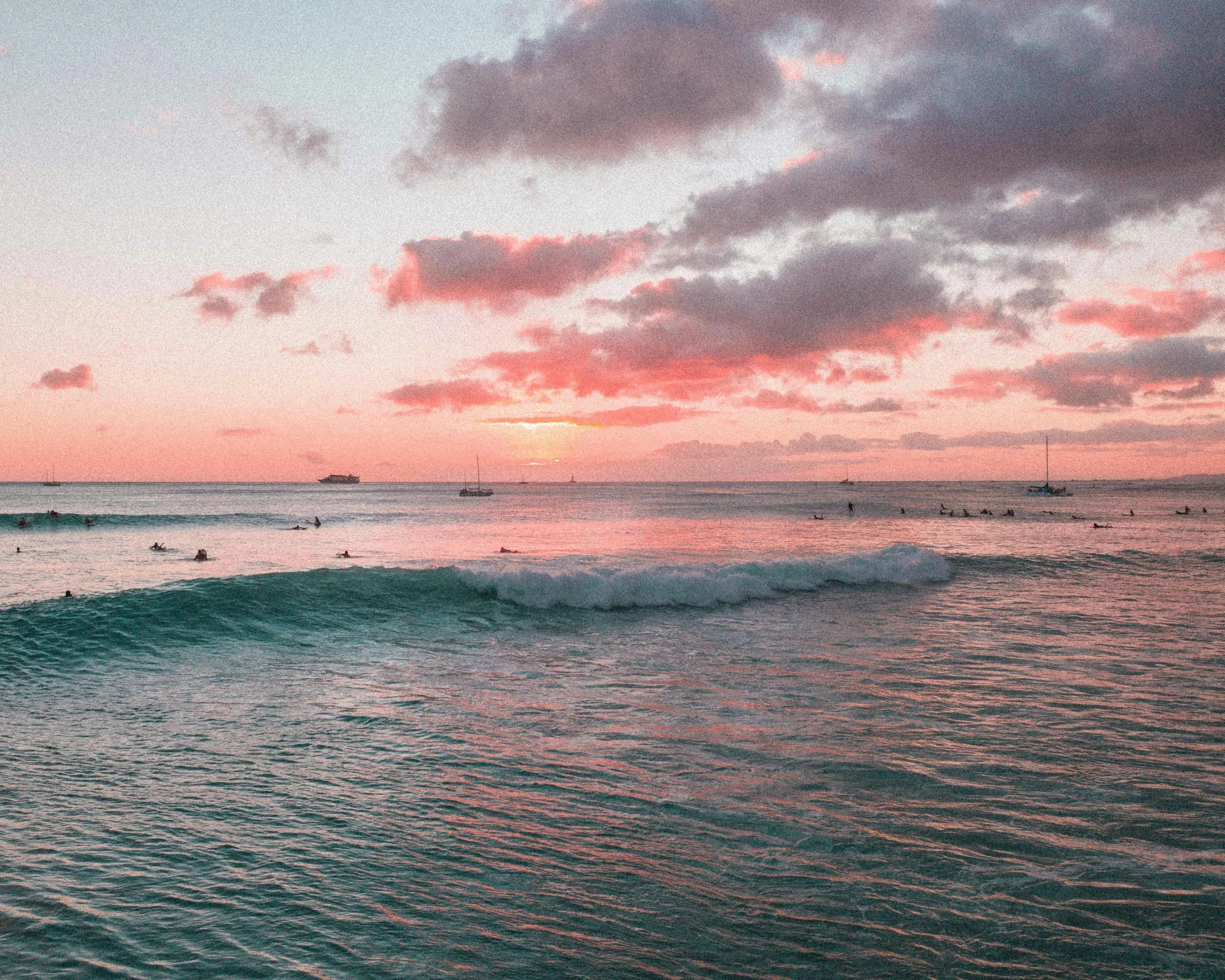 a pink sky is seen over the waves and sea