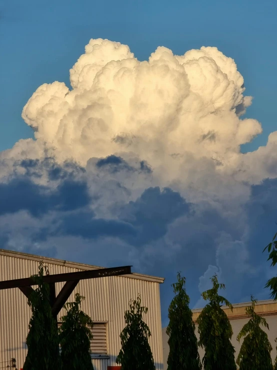 a huge cloud hovers over an industrial building