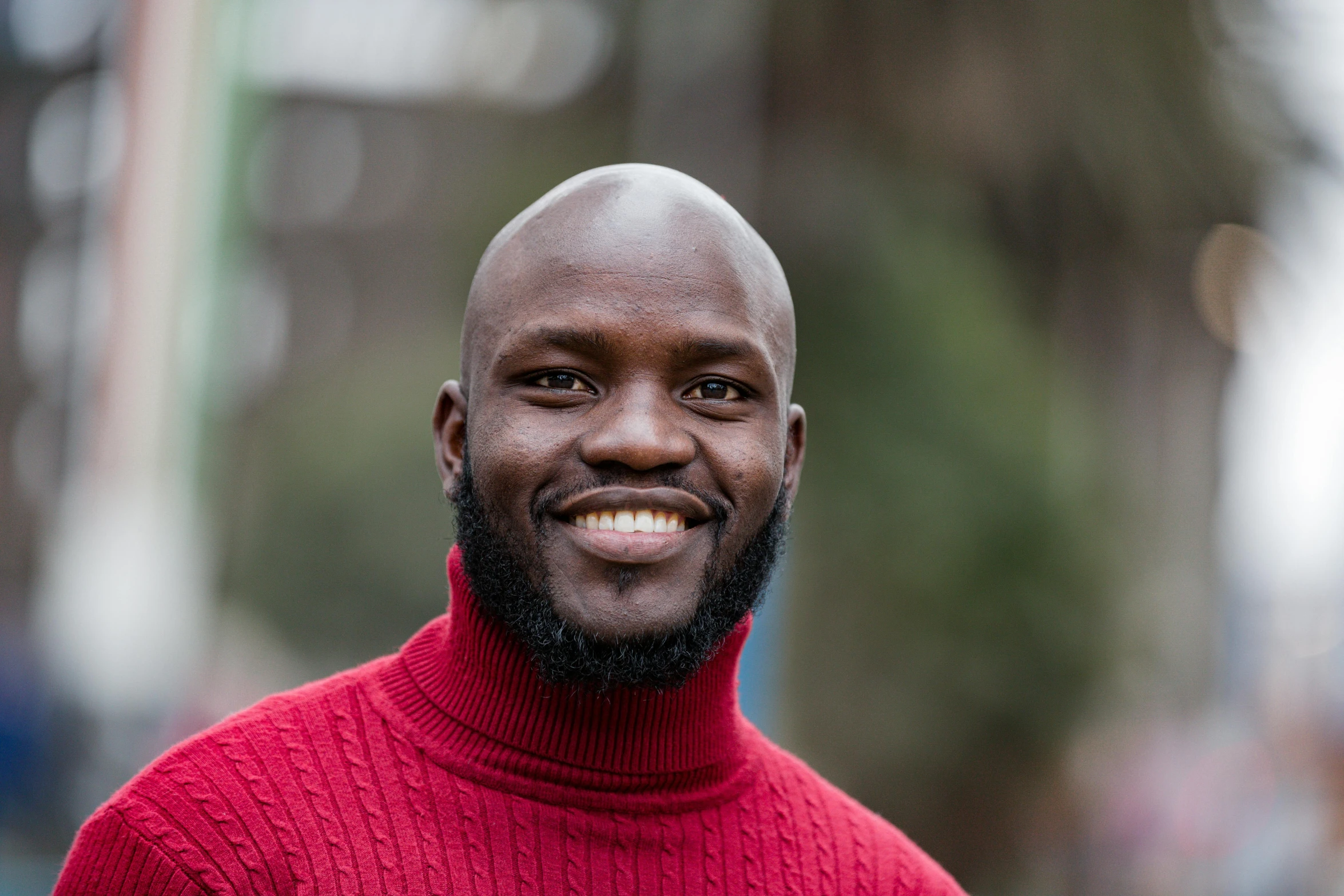 a bald headed man in a red sweater smiles