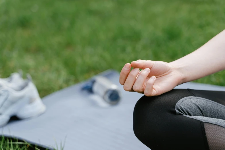 a person sits on a mat on the grass