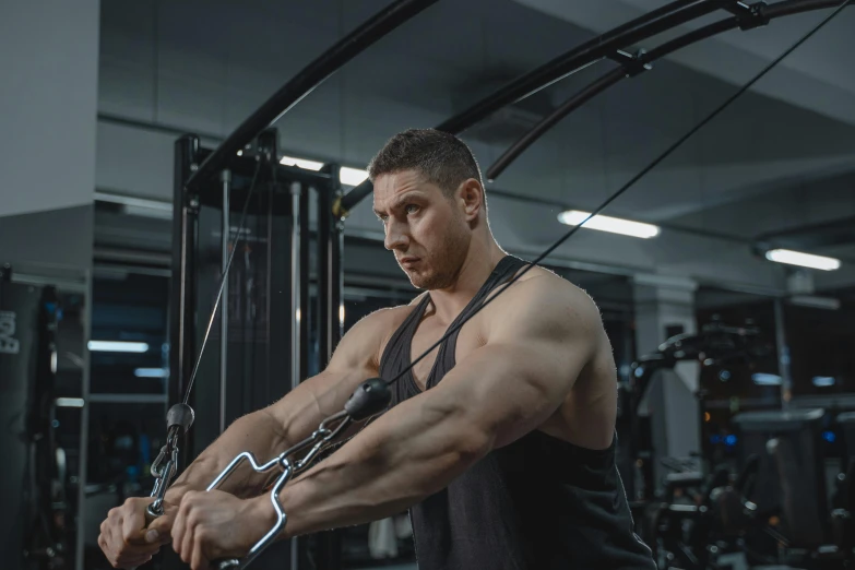 a man at the gym pumping his muscles with ropes