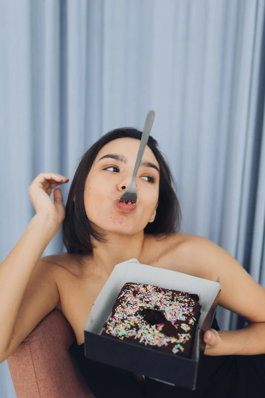 young woman wearing mask posing with doughnut on table
