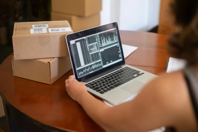 a person is sitting at a table and checking the status on their laptop