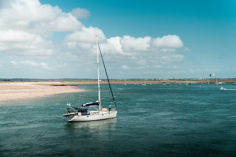 a small sailboat on the ocean by an industrial port