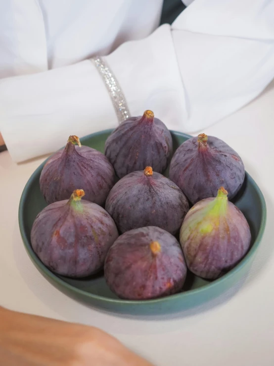 five purple figs with yellow stems on a green plate