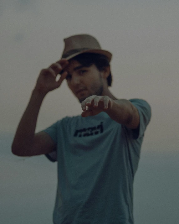 man standing with hand on his head and another person wearing a fedora