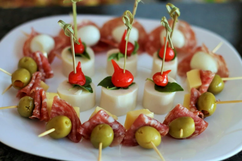 small appetizers are served with olives, cheese and meat