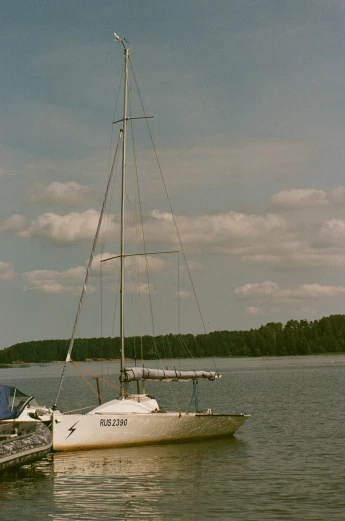a sail boat sitting in the water on a partly cloudy day