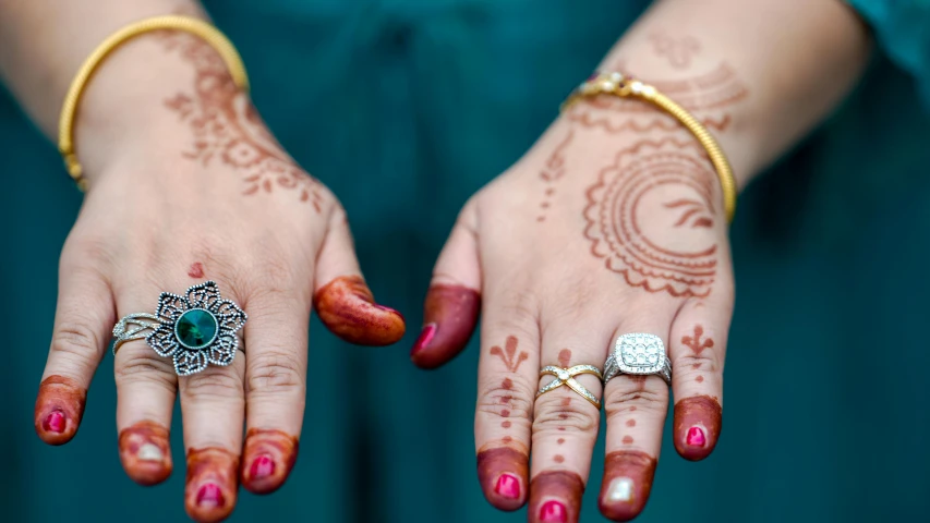 two hands with hendi and rings on their fingers