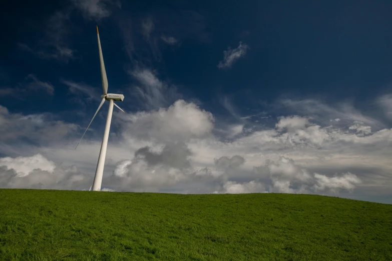 a wind turbine on top of a grassy hill