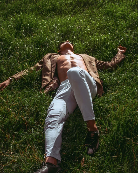 a man laying down on the grass in his pants