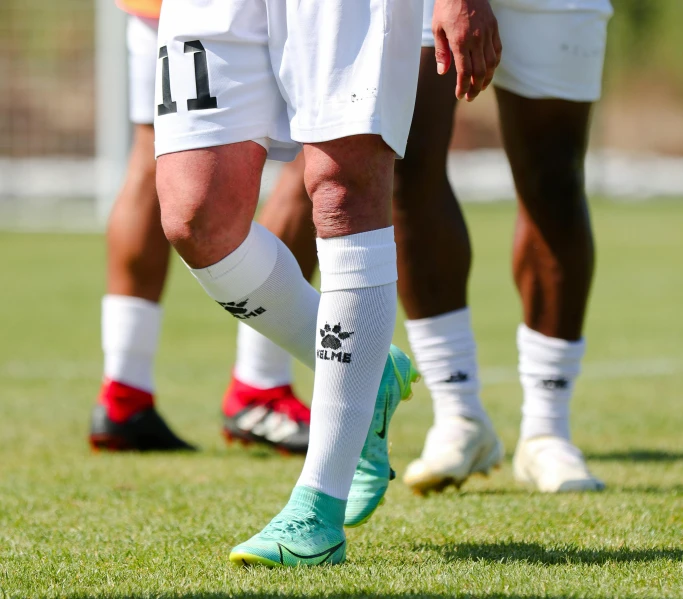 the legs of three soccer players standing around