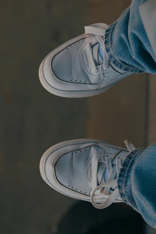 a person's feet standing on top of a street with blue jeans