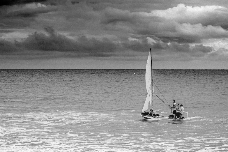 a man on a sailboat in the ocean under a cloudy sky