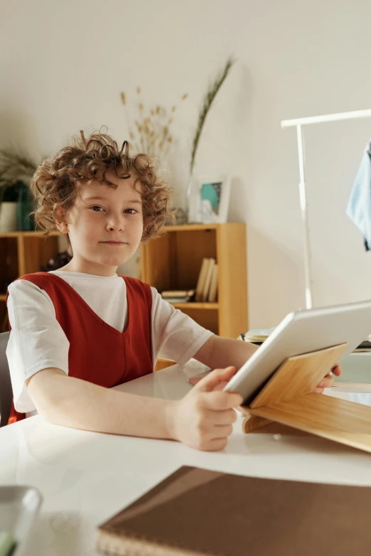 a boy wearing a red apron playing with a tablet