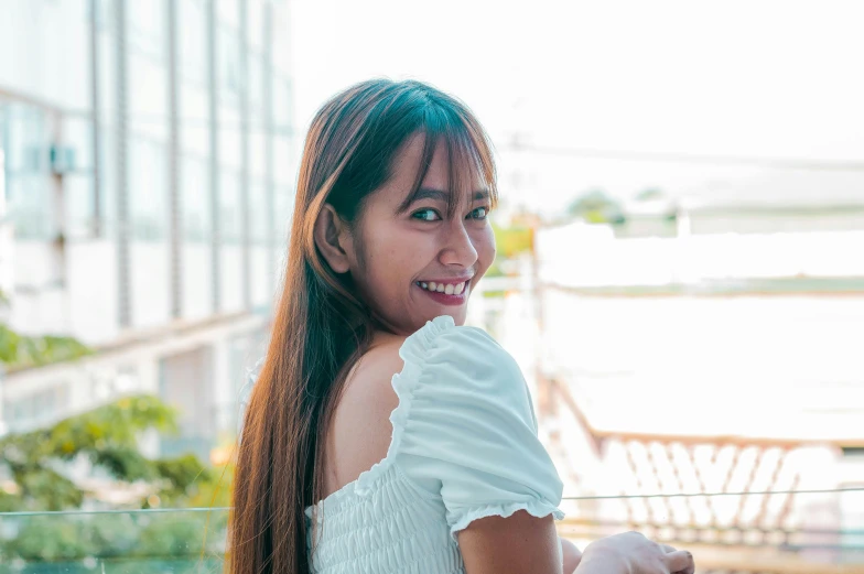 woman in short white dress smiling while looking at the camera