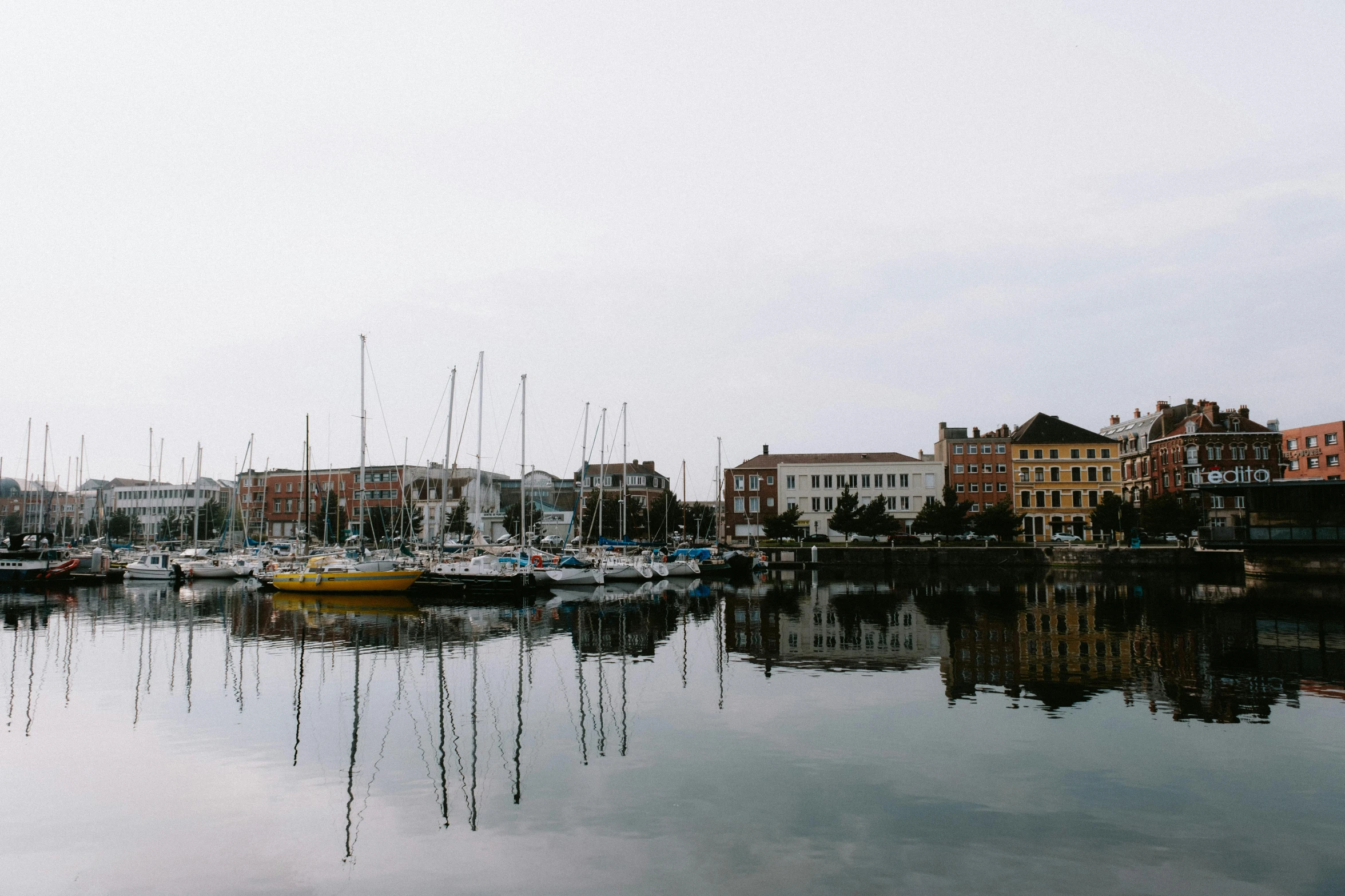 small boat sitting in the water at a harbor with lots of buildings