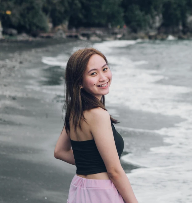 woman smiling while standing near the water on the beach