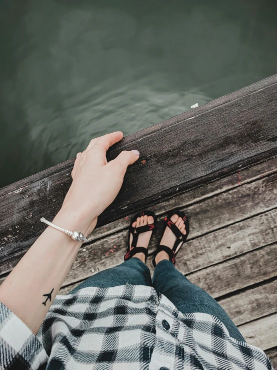 someone sitting on a dock looking down at the water