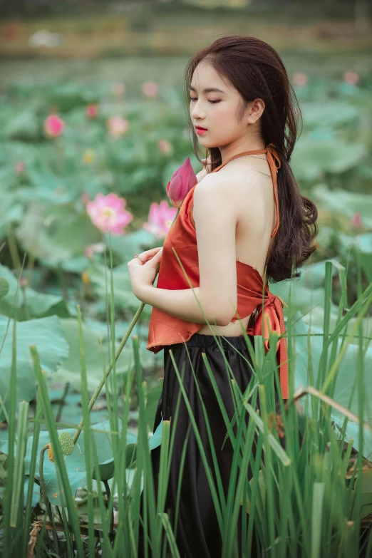 a young lady wearing a red top standing in the middle of a pond