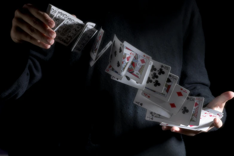 a person holds three deck cards in both of their hands