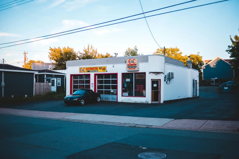 a small white building with an electric car in front