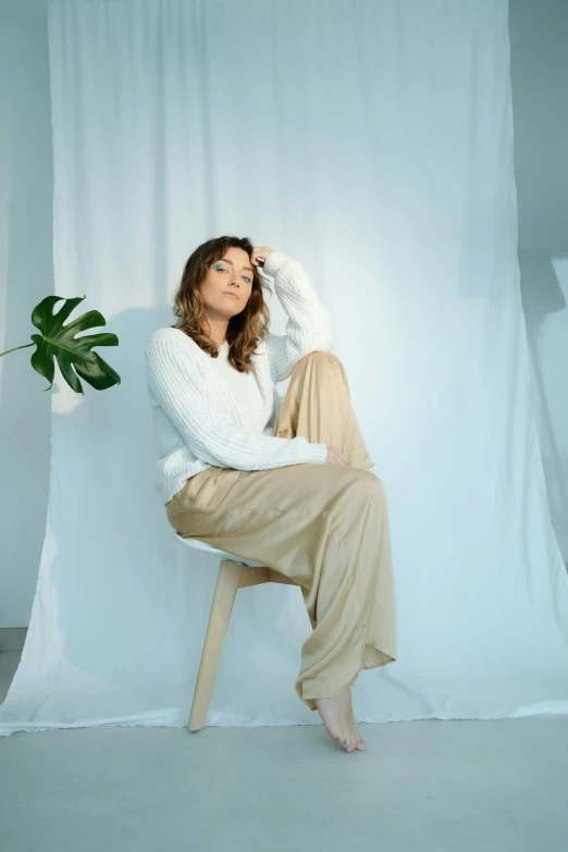 a woman sitting on top of a chair next to a plant