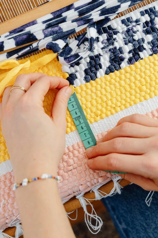 a woman using a green ruler to measure some colored fabric