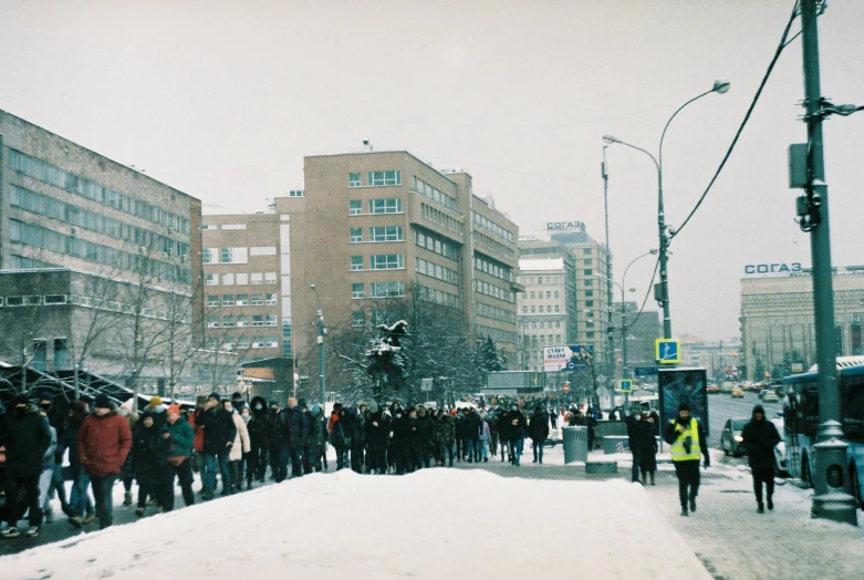 some people standing outside near the snow and some buildings