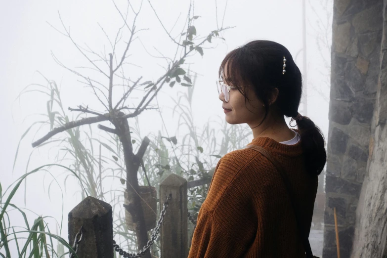 an asian woman standing in the fog with a bamboo tree